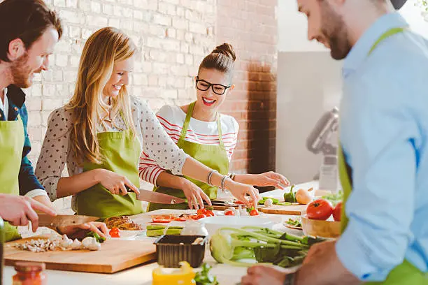 Group of people wearing aprons taking part in cooking class