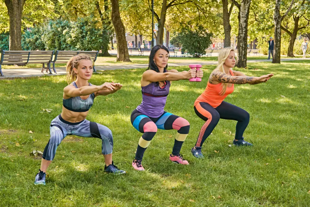 Three sporty women  doing squats in a park.